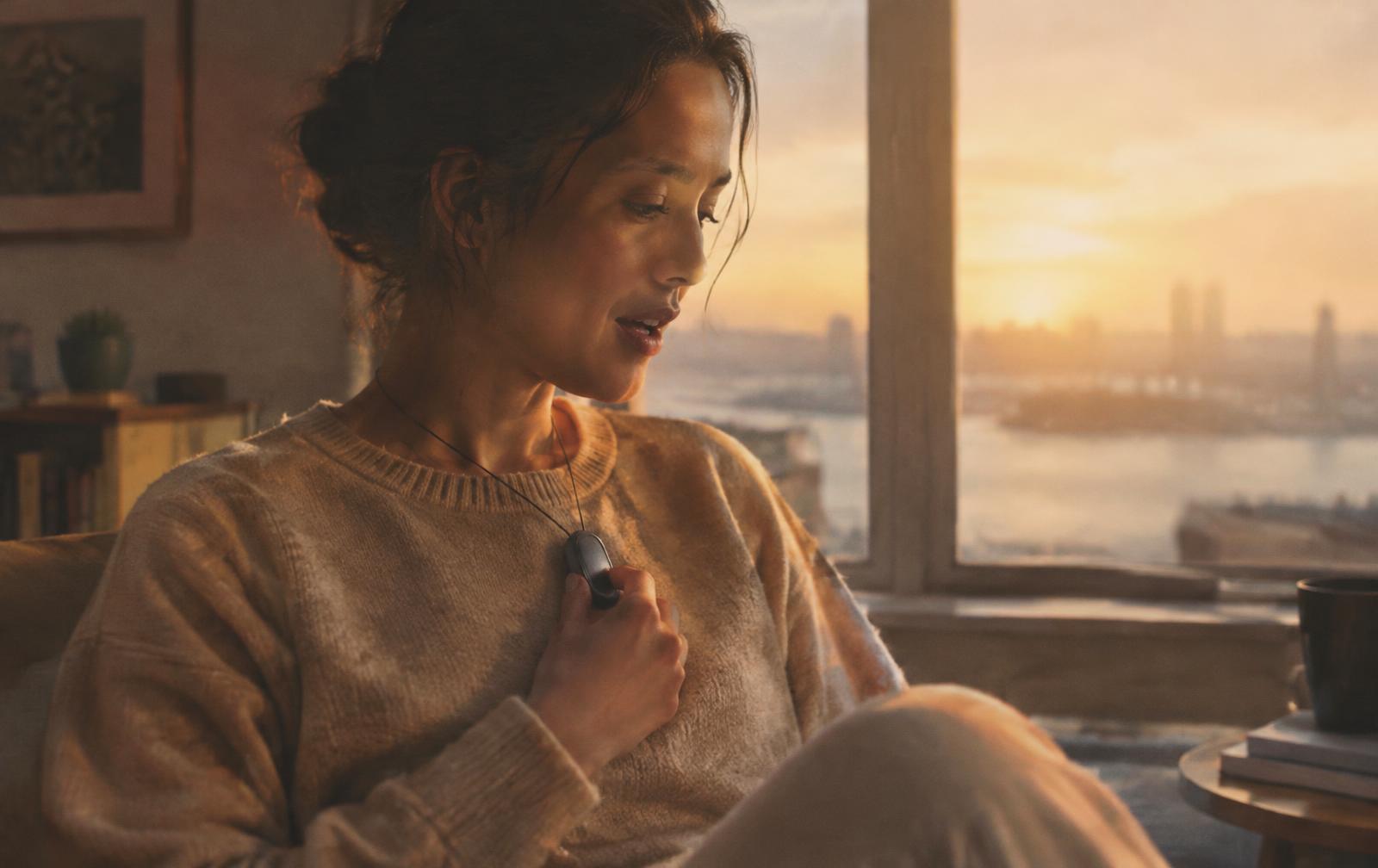 A woman speaking quietly to her Maimaind pendant at sunrise